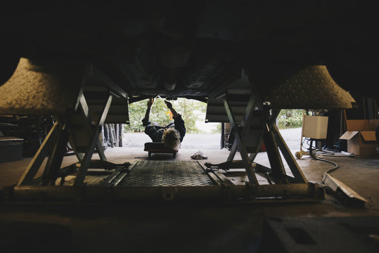 Underneath view of mechanic repairing car at auto repair shop
