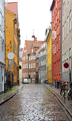 Colorful street, red, blue and yellow houses and bikes with basket in old town, rainy day, Copenhagen, Denmark - 170841688