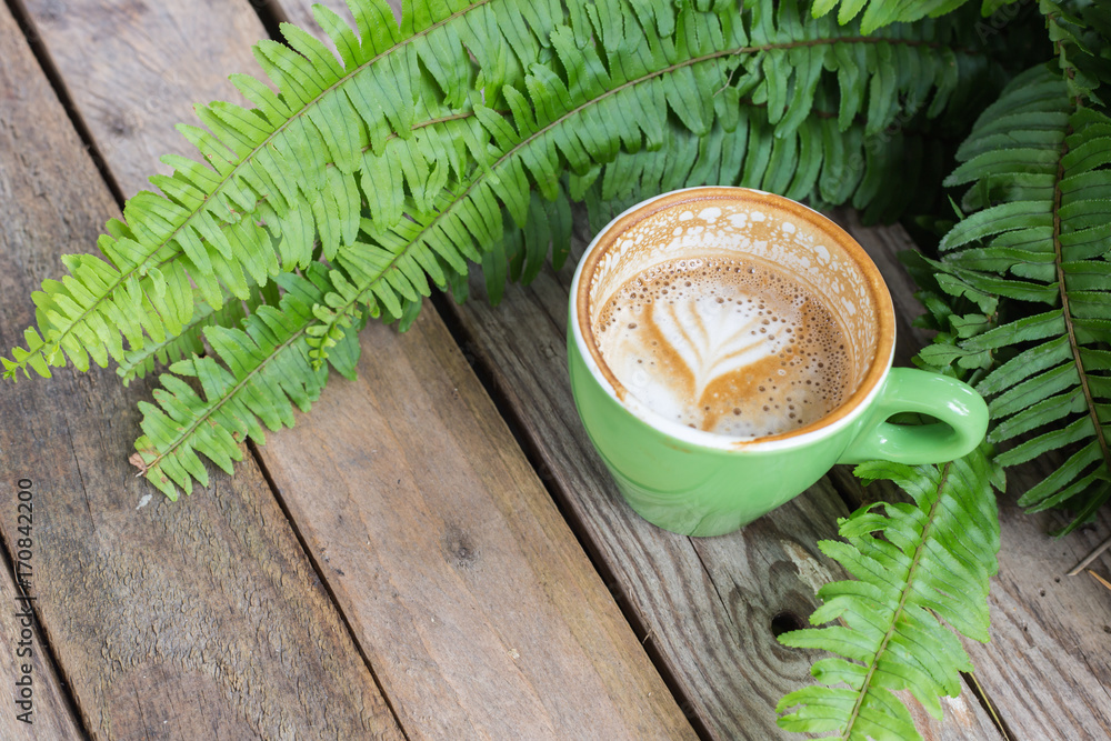 Wall mural coffee cup on wood table with fern leaf