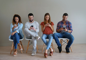 Young people in waiting room looking at smartphone