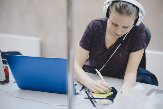 Female computer programmer writing on adhesive note while working in office