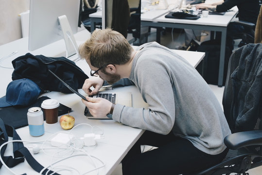 Side view of computer programmer fixing digital tablet to keyboard at desk in office