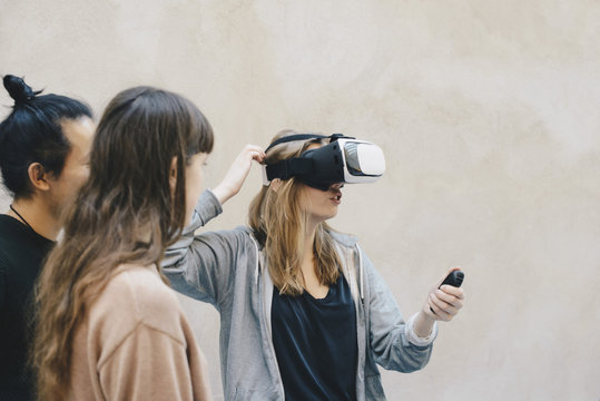 Computer programmer using remote control while wearing VR glasses by colleagues in office
