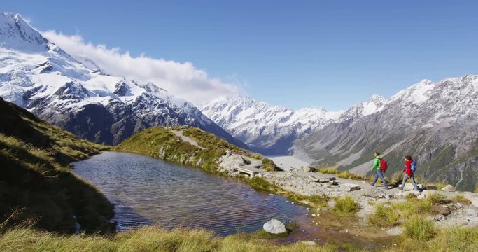 Hiking travel nature hikers in New Zealand. Couple people on hike trail route with Mount Cook landscape, walking on Sealy Tarns tramping route, famous tourist destination. RED EPIC.