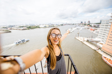 Young woman tourist making selfie portrait on the aerial landscape view background on Hamburg city,...