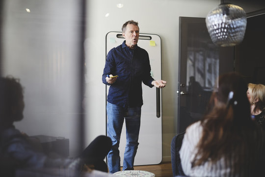 Mature businessman giving presentation to colleagues in board room