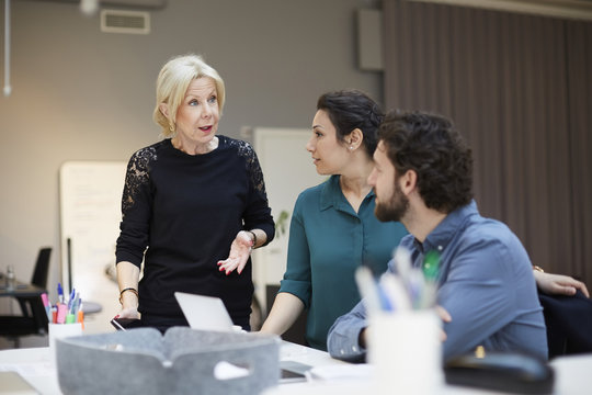 Senior female professional talking with colleagues at creative office