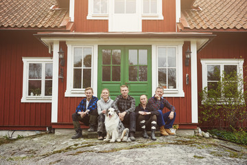 Portrait of family sitting with Australian Shepherd at entrance of house
