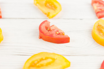 Slices red and yellow ripe fresh tomatoes on old white rustic wooden planks