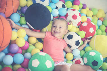 Fototapeta na wymiar Caucasian girl lying on colored ball. Little girl playing in playground.