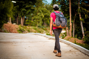 Fototapeta premium man traveling walking with backpack at national park in the jungle day time sun shine on holiday at weekend relax fresh on background nature view