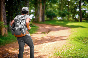 man traveling walking with backpack at national park in the jungle day time sun shine on holiday at weekend relax fresh on background nature view