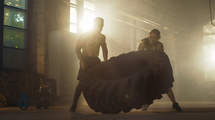 Fit Athletic Woman Lifts Tire Under Supervision of Her Partner/ Trainer, as Part of Her Cross Fitness/ Bodybuilding Gym Training.