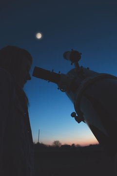 Girl looking at the stars and full Moon through a telescope. My astronomy work.