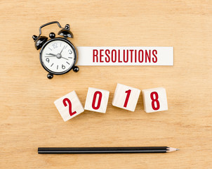 Resolutions 2018 new year red on wood cube with pencil and clock top view on wood table,New year business concept.