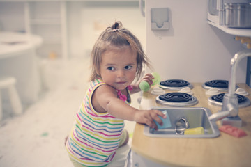 Little Caucasian baby in playground. Little girl playing with toys.