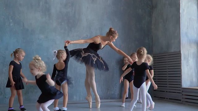 Teachers show how to dance to little ballerinas. Girl dancer in ballet school learns to dance. Young ballerinas jumping in training. School of ballet. Feet closeup