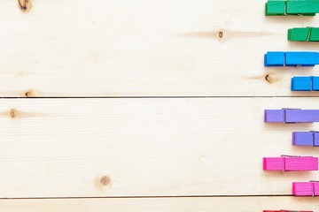 colored wooden clothespins on wooden background, top view with copy space