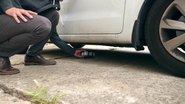 A man puts a homemade explosive device under the car. Preparation of terrorist act. 4k. Slow motion