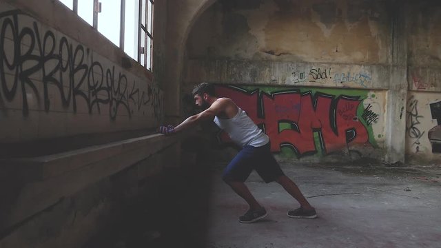 Fit male boxer leaning on a sink in an old abandoned building. Slow motion.