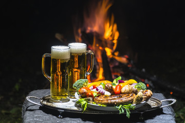 two glasses of beer on the background of fire