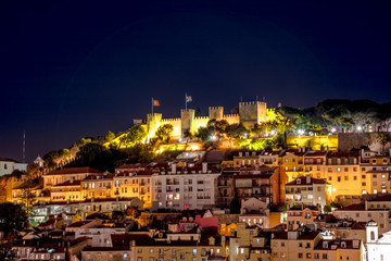Scenic aerial view of Lisbon panorama by night. Architecture background. Details of Sao Jorge Castle or Fortress of Saint George from platform of Elevador de Santa Justa tourist attraction in Baixa.