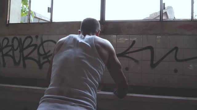 A fit young man doing push-ups on a sink in an old abandoned factory.