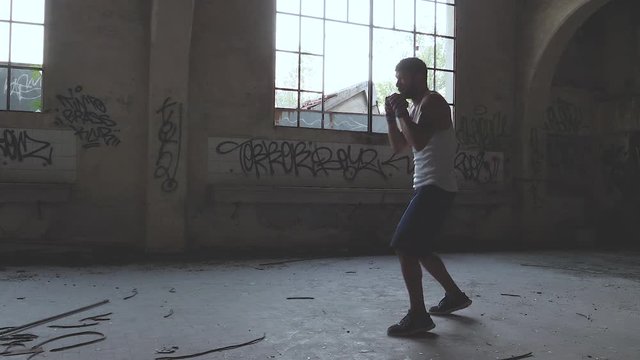 Muscular male boxer doing boxing exercise in an old abandoned building.