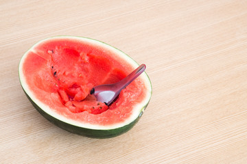 Eating a half piece of watermelon on wood background