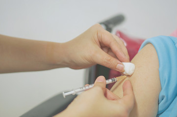 Nurse holding hypodermic syringe and cotton ball has injected vaccine