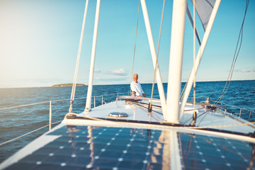 Smiling mature man standing on the deck of his sailboat