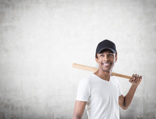 Smiling African American guy with a bat, concrete