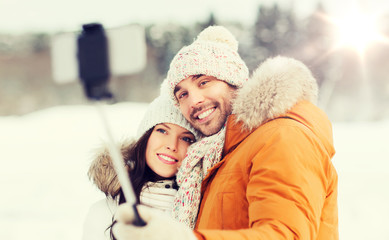 happy couple taking selfie by smartphone in winter