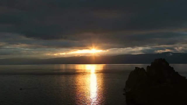 Beautiful colorful sunset at the Lake Baikal with dramatic clouds and sun shining.