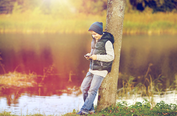 happy boy playing game on smartphone outdoors