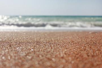 Beach summer scene with sea waves and sand on tropical vacation destination. Empty background with sandy texture close up center focus view. Blurred copy space holiday, travel, tourism concept theme