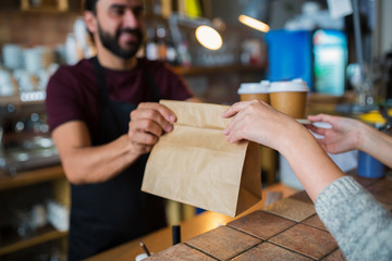 man or bartender serving customer at coffee shop