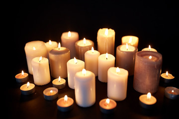 candles burning in darkness over black background - obrazy, fototapety, plakaty