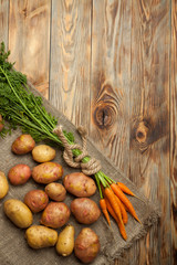 Raw potatoes and carrots on a wooden background