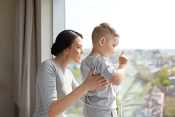 mother and son looking through window at home