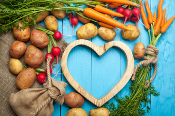 Raw potatoes, radishes and carrots on a blue wooden background
