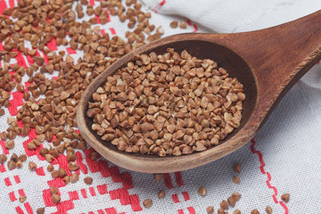 Wooden spoon with buckwheat on the towel. Background of buckwhea