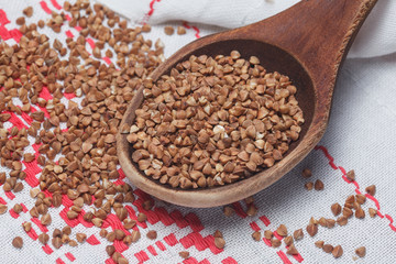 Wooden spoon with buckwheat on the towel. Background of buckwhea