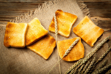 Toasts of bread and wheat on an old wooden background