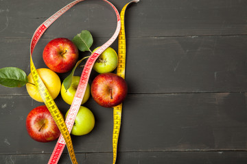 Diet and centimeter, apples on a black wooden background