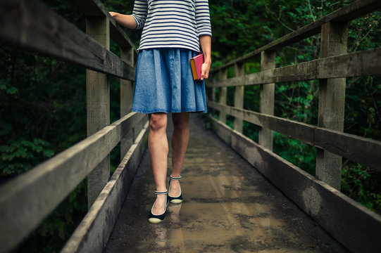 Woman with book on bridge in forest