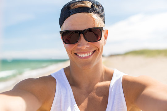 man in sunglasses taking selfie on summer beach
