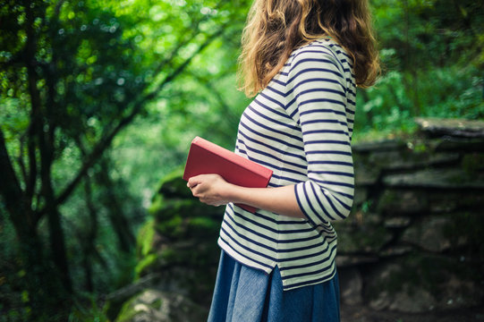 Woman with book standing in the forest