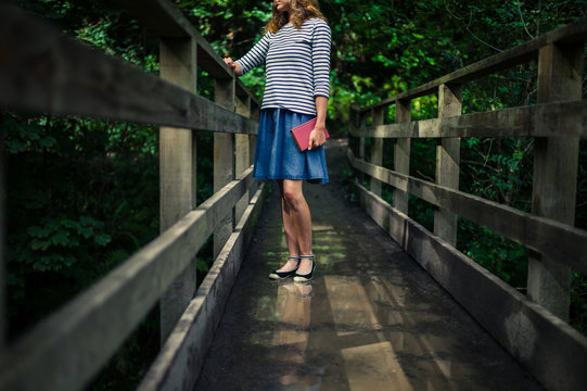 Woman with book on bridge in forest