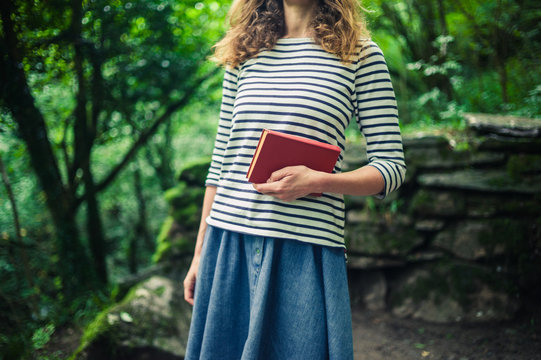 Woman with book standing in the forest